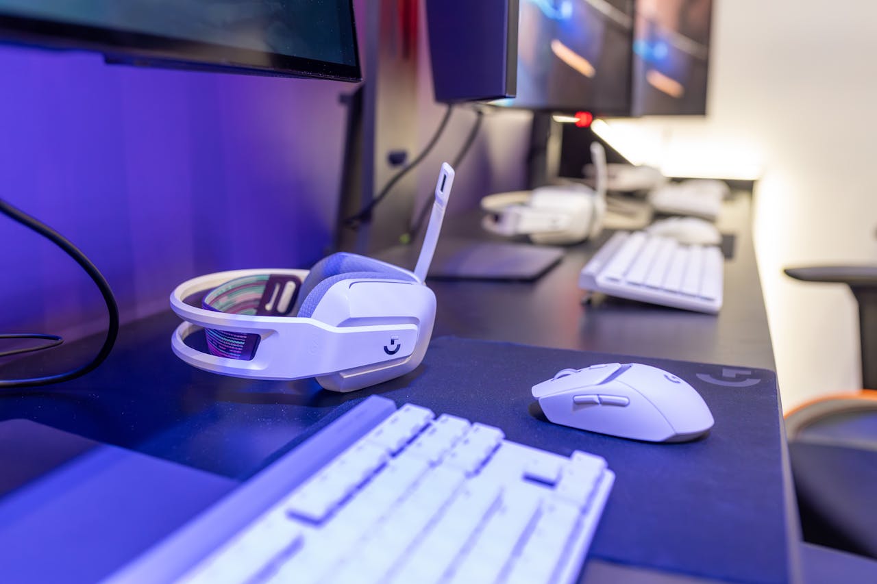 Close-up of a gaming setup featuring a white headset, computer mouse, and keyboard with a vivid lighting ambiance.